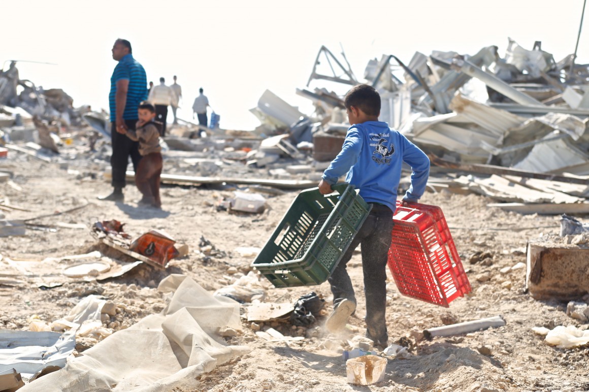 Kamal Al Jabari walks with his two sons as they help to salvage what is left. (Photo: Kelly Lynn)