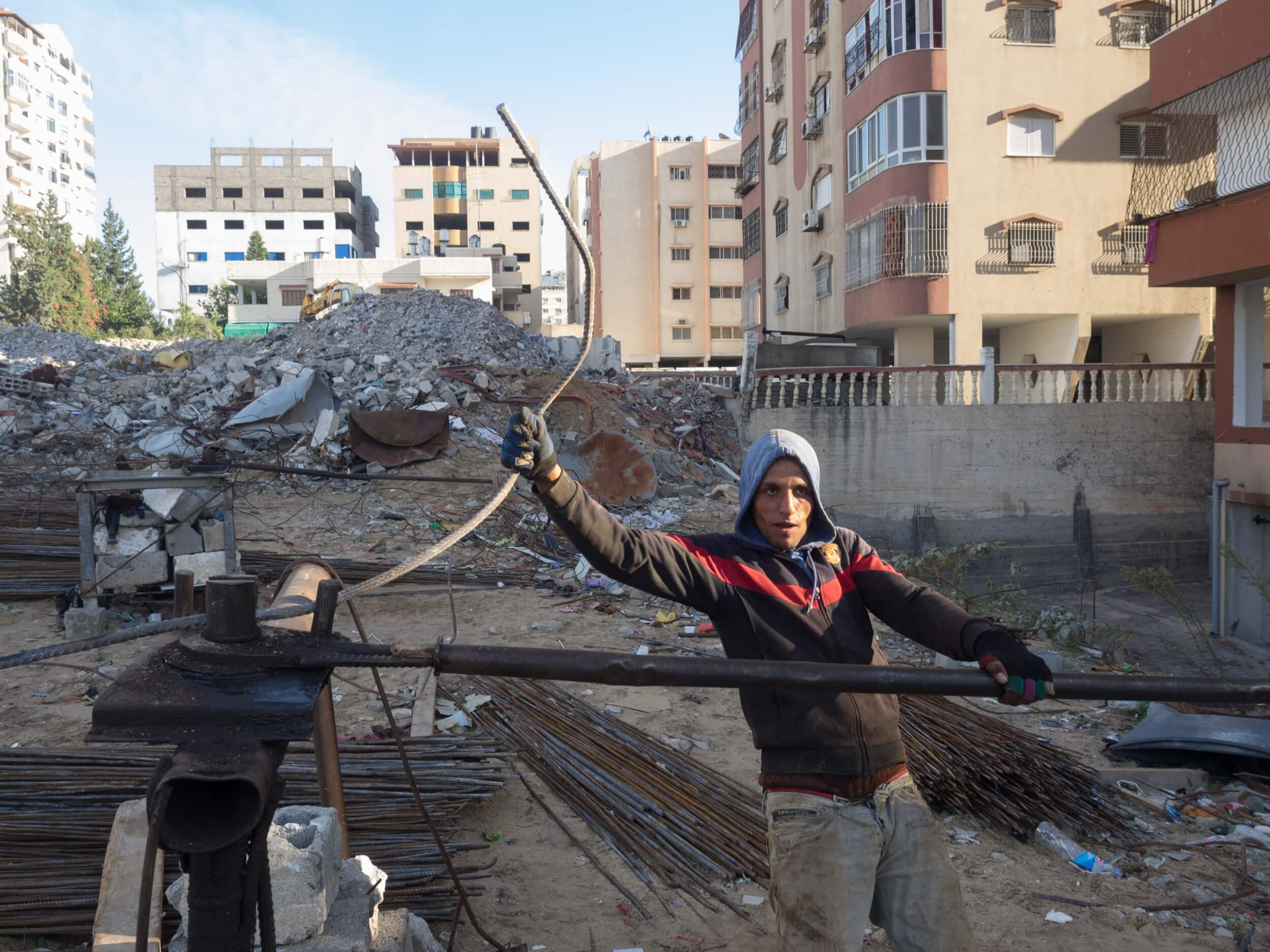 Mohammed Shukri Mohammed Khrewat, 21, works to straighten rebar from the rubble of the Zafer 4 Tower. (Photo: Dan Cohen)