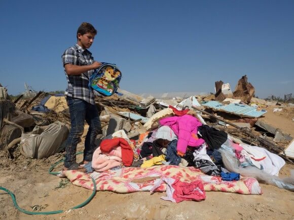 Abdullah Hassan combs through belongings where the house was bombed, in Gaza, photo by Dan Cohen