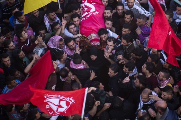 Khalid's mother helps to carry his body during Bethlehem funeral