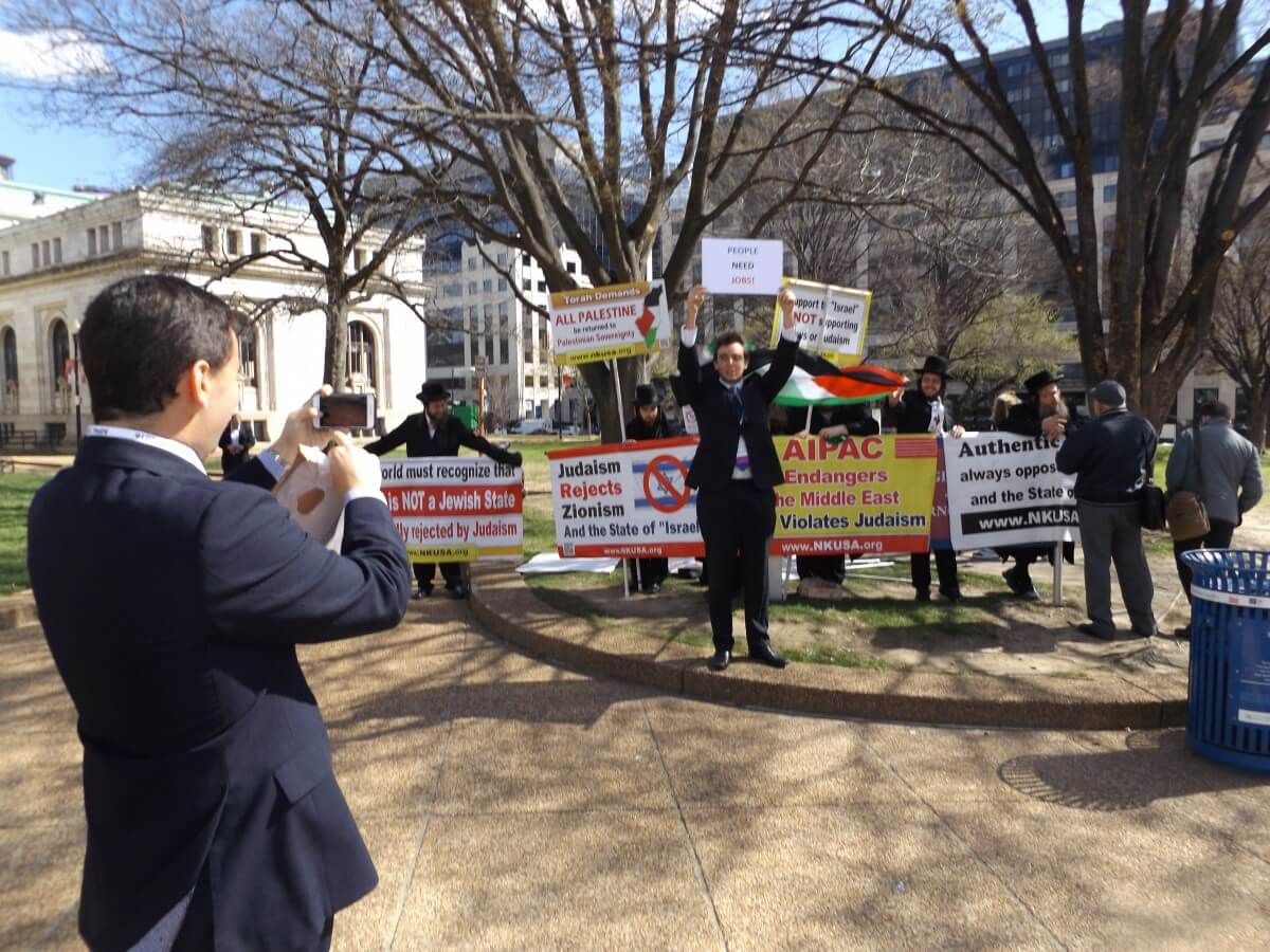 AIPAC attendees stand in front of the Neturei Karta protest. 