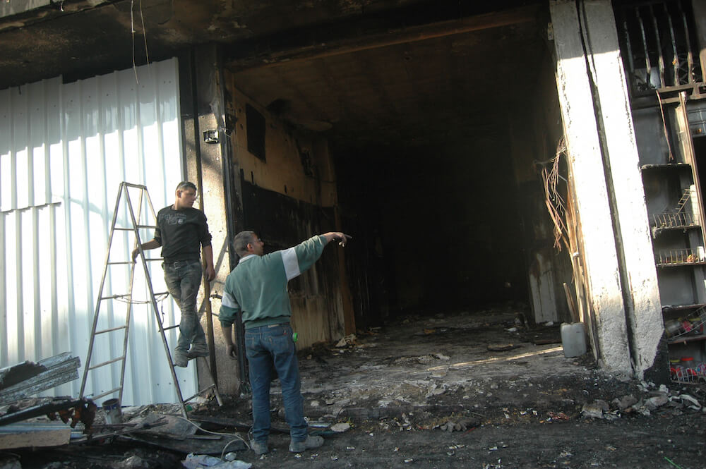 Palestinian assess damage to a West Bank shop burned beyond repair in a fire started by the Israeli military, al-Bireh. (Photo: Allison Deger)