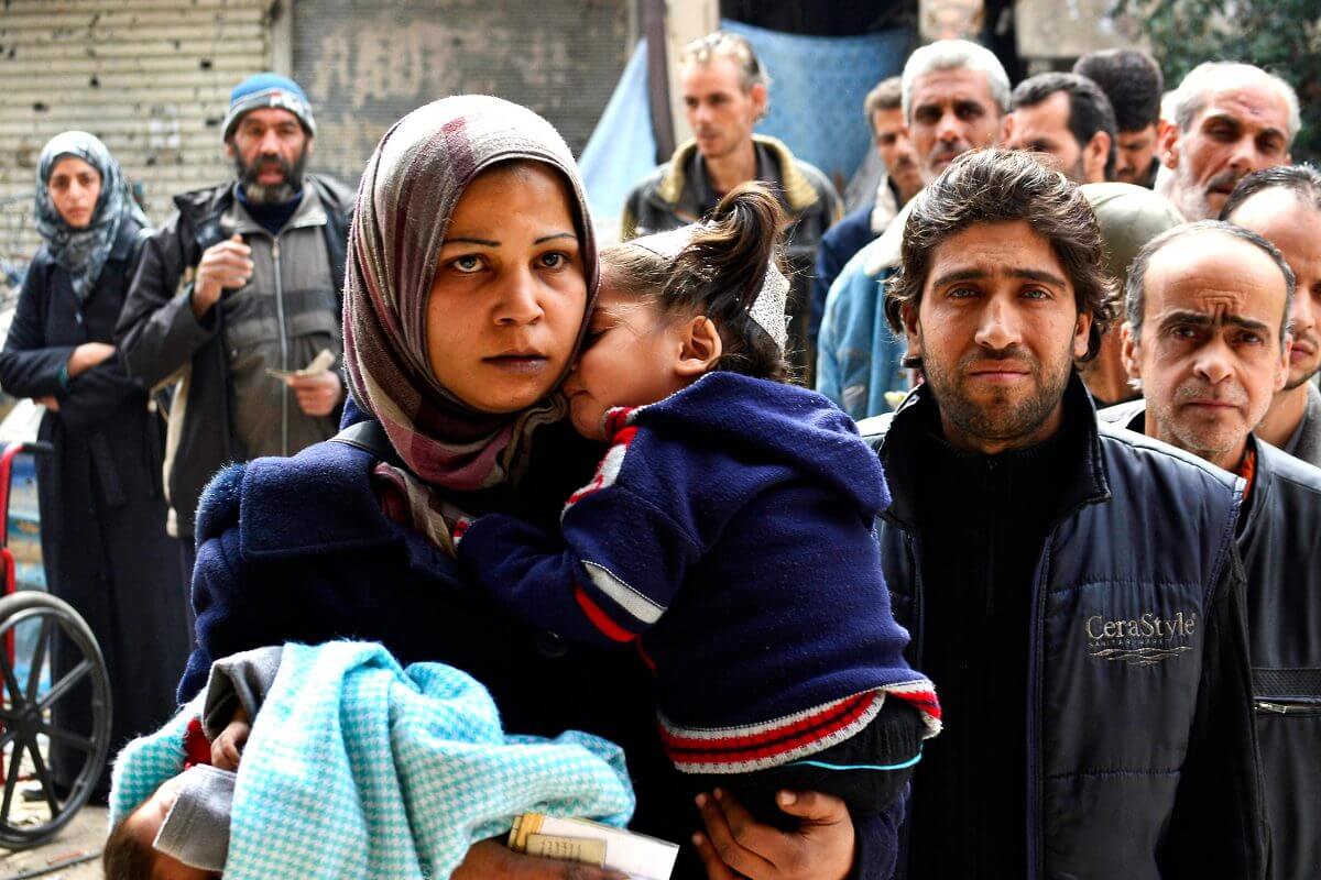 Residents queue up to receive humanitarian aid at the Palestinian refugee camp of Yarmouk, in Damascus, Syria, March 11, 2015.