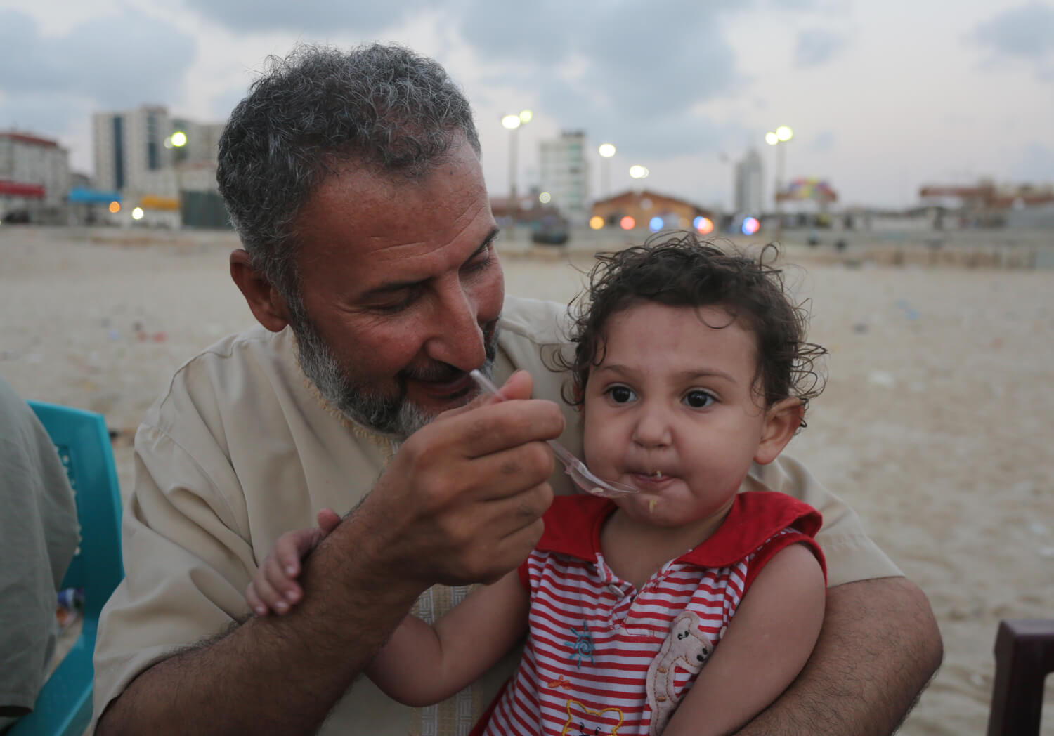 Nihad Hassan,53, feeds his granddaughter, Seba, 2 on the beach in Gaza, June 27, 2016.