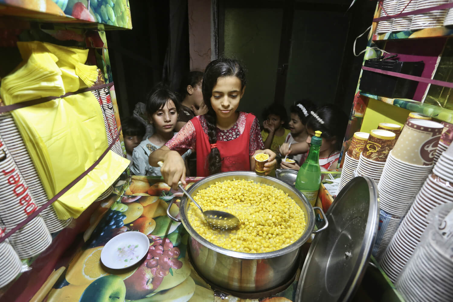 Mervit Baker, 12, sells cups of buttered corn in front of her house in the Al- Zaytoon area, Gaza, June 27, 2016. (Photo: Mohammed Asad) 