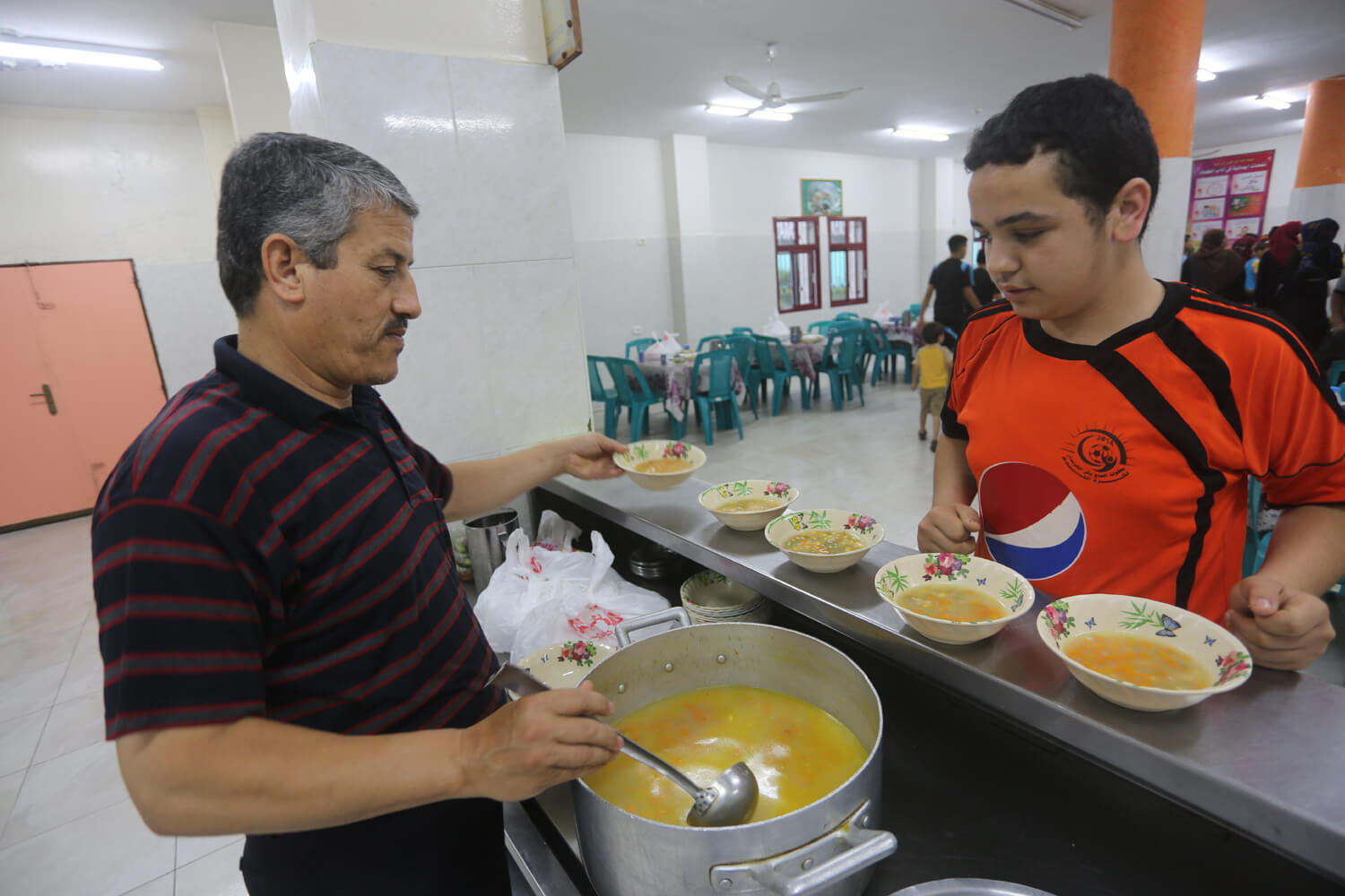 Ahmad Harb, 13, receives a meal from the cook at the Al-Amal Institute for Orphans, June 26, 2016. (Photo: Mohammed Asad)