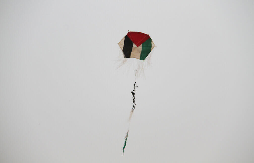 Palestinian children fly a kite with colours of the national flag at the site of protest tents next to the Gaza Strip's border fence with Israel, east of Gaza city, on May 10, 2018. Photo by Mahmoud Ajour