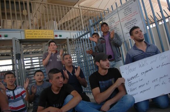 Palestinians hold signs in protest of a-Zeitim checkpoint. The demonstrators want to pass between Jerusalem neighborhoods without crossing a checkpoint. (Photo: Allison Deger)