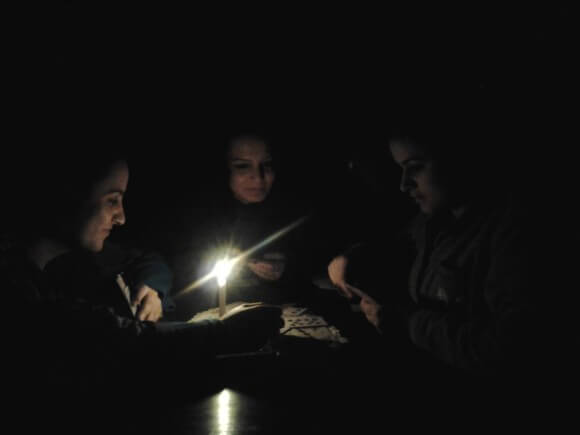 Sarah and her sisters reading books by candlelight during power outage in Gaza