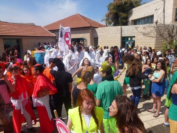 Purim carnival, students in KKK robes and black face in the background. (Photo: Harel High School/Flickr)