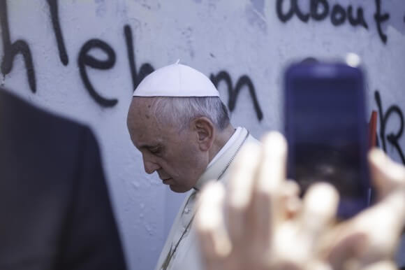 Pope Francis backs up slowly with his head bowed after praying at the military gate in the Israeli built Apartheid Wall on May 25th, 2014. (Photo: Kelly Lynn) 