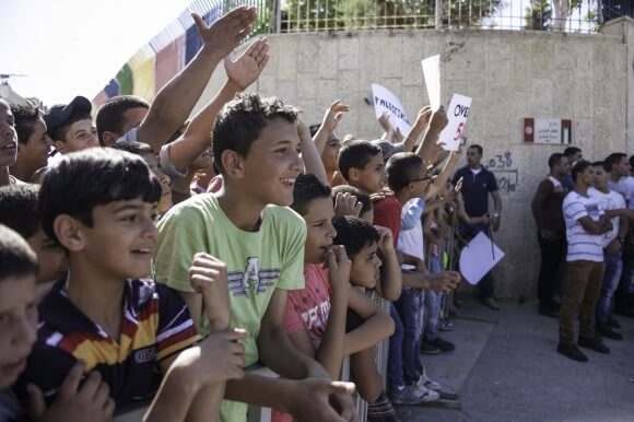 Children from Dheisheh Refugee Camp wave as Pope Francis passes in a caravan on his way to meet with young refugees from Bethlehem's three camps, Dheisheh, Aida and Azza, on May 25th, 2014. (Photo: Kelly Lynn)