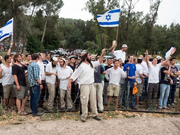 A crowd of Israelis celebrating in a nearby park gather next to the highway to taunt Palestinians walking by. (Photo: Dan Cohen)