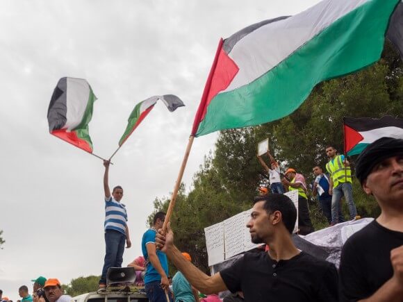 Palestinian men wave flags during Nakba Day commemoration at the site of the village of Lubya, near the northern city of Tiberias in the Galilee. (Photo: Dan Cohen)