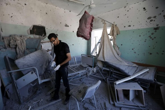 A Palestinian employee inspects damages at the Al-Aqsa Martyrs hospital in Deir al-Balah, in the central Gaza Strip, after the building was shelled by the Israeli army on July 21, 2014, killing five people and wounding at least 70. (Photo: Mohammed Abed/AFP)