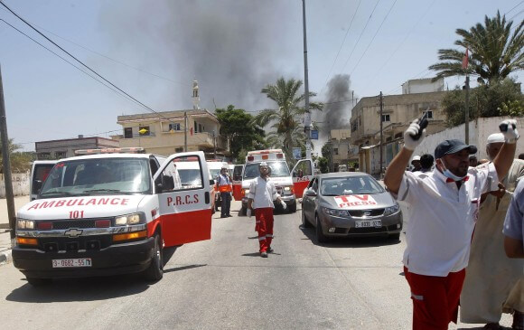 Smoke rises after a shell fired by the Israeli army slammed into a building near ambulances as medics reported that they were waiting to evacuate wounded people from the town of Khuza'a, east of Khan Yunis in the southern Gaza Strip, on July 23, 2014. (Photo: AFP Photo / Said Khatib)