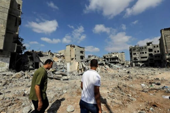 Palestinians walk past the rubble of houses destroyed by Israeli strikes in Beit Hanoun, northern Gaza Strip, Sunday, July 27, 2014. (Photo: Lefteris Pitarakis, AP)