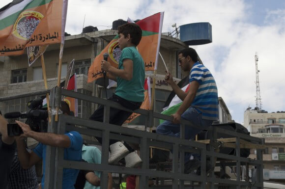 A young boy leads the beginning of the chants for Gaza while riding on a truck equipped with speakers.  (Photo: Sheren Khalel)