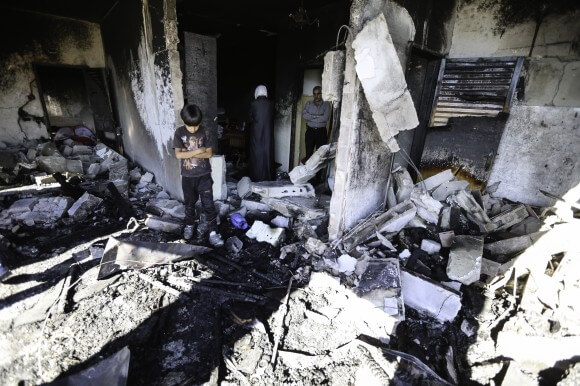 A neighbor boy stands amidst the rubble of the second floor living room. (Photo: Kelly Lynn)