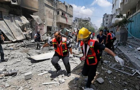 Palestinian medics carry a casualty as they run past a burning building in Gaza City's Shijaiyah neighborhood, Sunday, July 20, 2014. (Photo: AP/Lefteris Pitarakis)