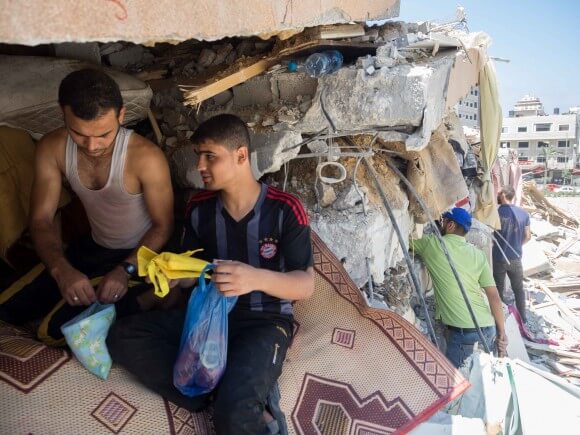Men search through the destruction of their respective homes. (Photo: Dan Cohen)