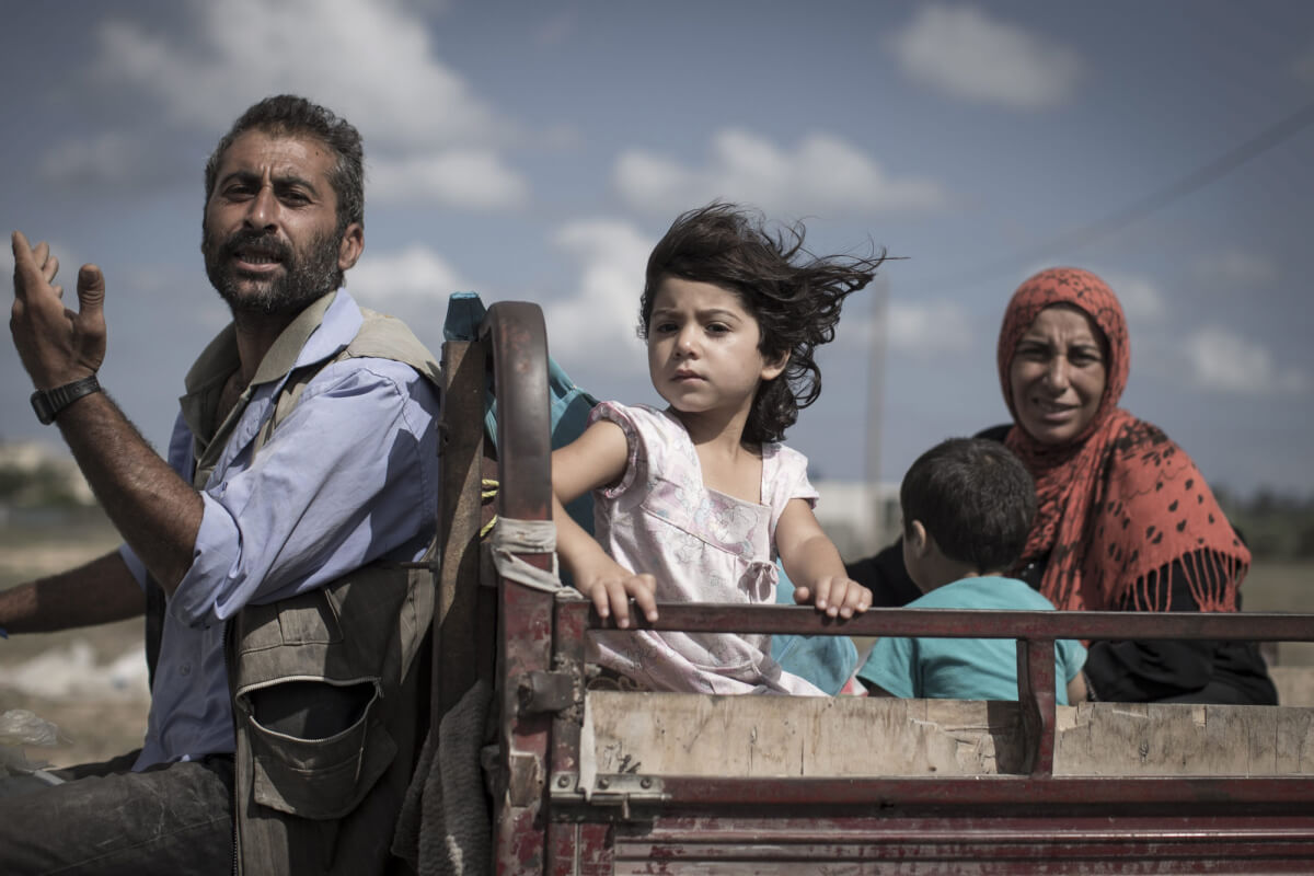 A Palestinian family who fled their homes en route to seek shelter. Gaza Strip, July 18, 2014 (photo: Oliver Weiken/EPA)