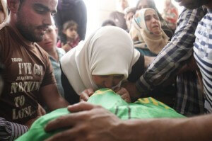 The mother of Amer Abu Aisha kisses the lifeless body of her son after Israeli troops shot dead two Palestinians including Aisha and Marwan Qawasmeh in the West Bank city of Hebron, Tuesday, Sept. 23, 2014. (Photo: Nasser Shiyoukhi/AP)
