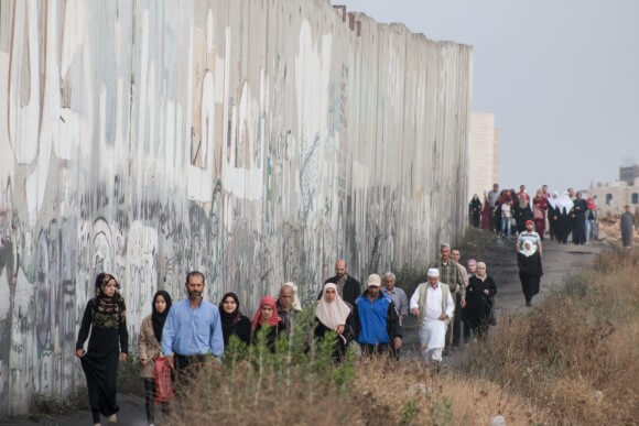 Un folto gruppo di Jenin cammina lungo il muro di separazione diretto a Qalandia per accedere a Gerusalemme, giugno 2015 (Foto: Karam Saleem)