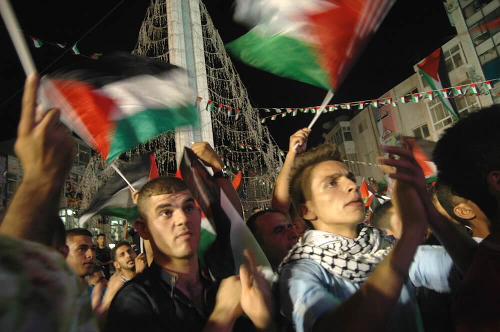 Palestinians cheer for the raising of the Palestinian flag at United Nations headquarters in a celebration held in downtown Ramallah. (Photo: Allison Deger)