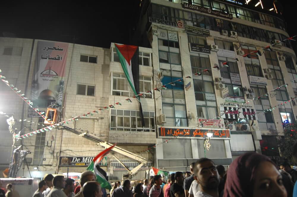 Palestinian flags draped over building in downtown Ramallah to mark the raising of the Palestinian flag at United Nations headquarters in New York City. (Photo: Allison Deger)