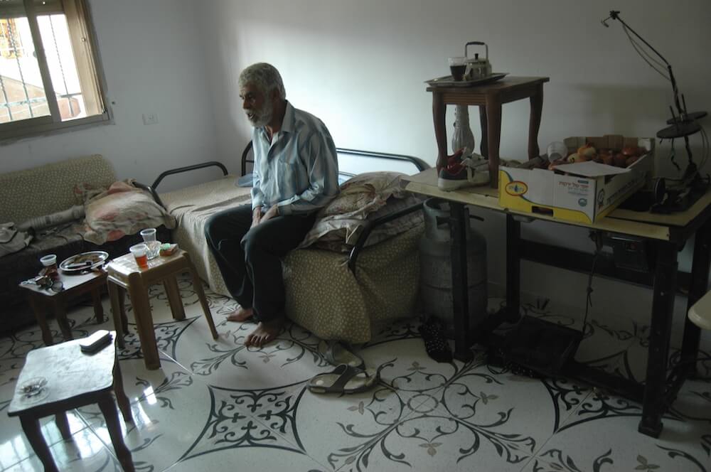 Abdallah Abu Nab sits in the living room of his family's new apartment, across the street from the home he was evicted from on Monday. (Photo: Allison Deger)