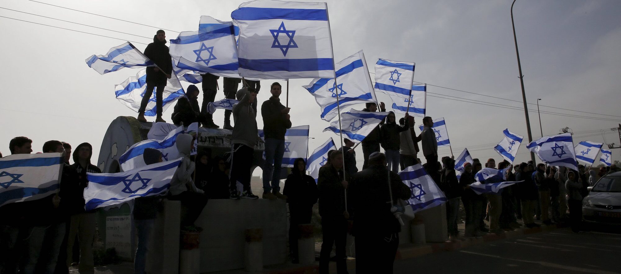 Israelis wave flag near the West Bank Jewish settlement of Efrat January 18, 2016. (Photo: REUTERS/Ronen Zvulun)