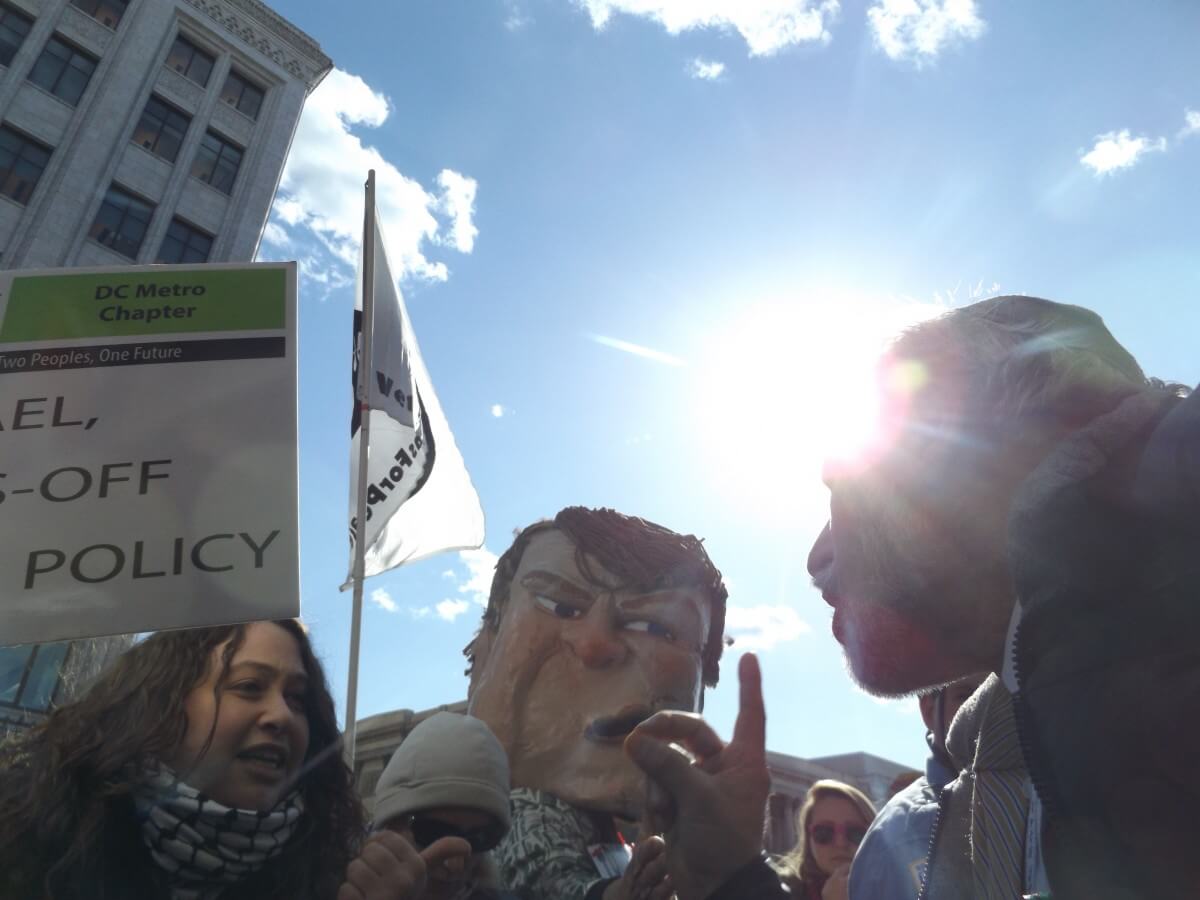 On the left, protester Emily Siegel, and on the right, AIPAC member Eliezer May, 66, from Rockville, Maryland. May and thousands of other AIPAC attendees shuffled in a blocks-long line past a corner where protesters had set up its picket line. (Photo: Wilson Dizard)
