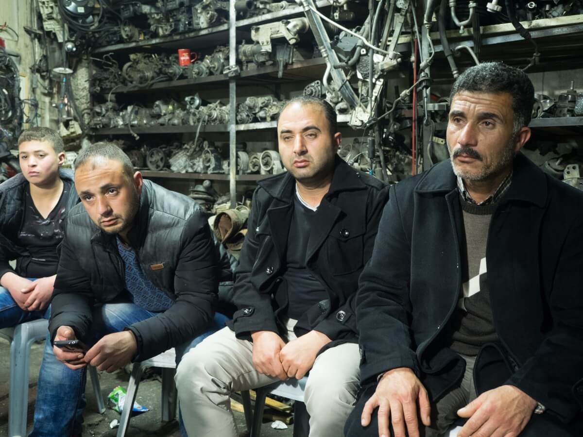 Aziz al-Qasrawi and family members sit in the mechanic garage they own. (Photo: Dan Cohen)