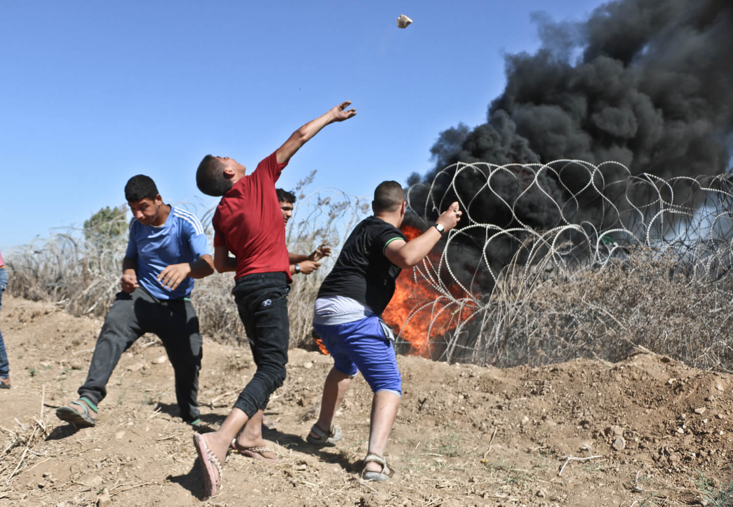 Young demonstrators burn tires on the barbed wire and throw stones on Israeli soldiers near Nahal Oz, east of the al-Bureij refugee camp in central Gaza Strip, September 30, 2016. (Photo: Mohammed Asad)