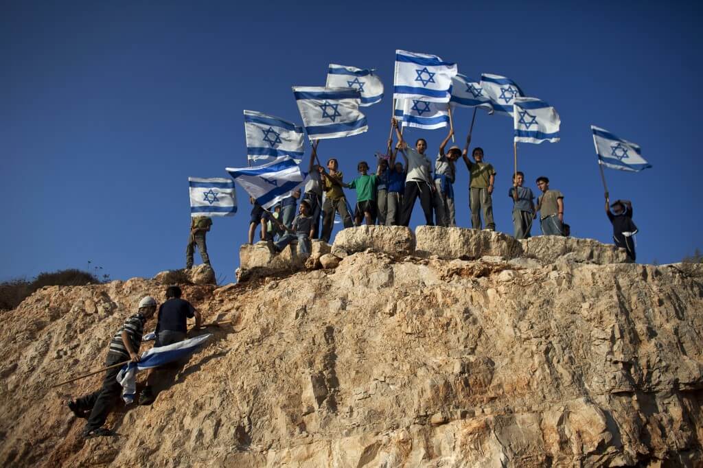 Jewish youth hold Israeli flags at the beginning of a rally march in the West Bank settlement of Itamar, near Nablus September 20, 2011. (Photo: REUTERS/Nir Elias)