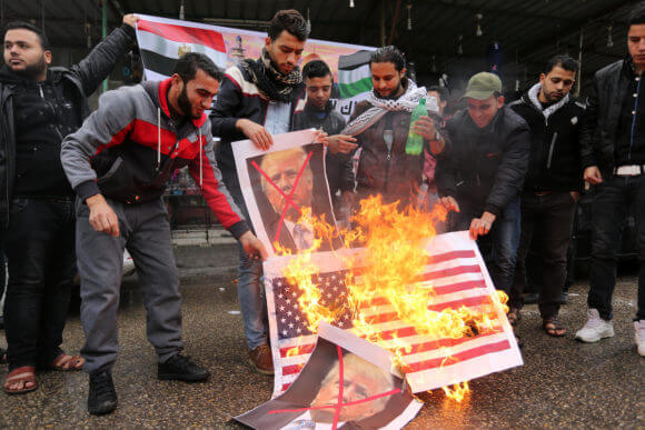 Palestinians burn posters depicting U.S. President Donald Trump and Israeli Prime Minister Benjamin Netanyahu during a protest against the U.S. intention to move its embassy to Jerusalem and to recognize the city of Jerusalem as the capital of Israel, in Rafah in the southern Gaza Strip December 6, 2017. (Photo: Ashraf Amra/APA Images)