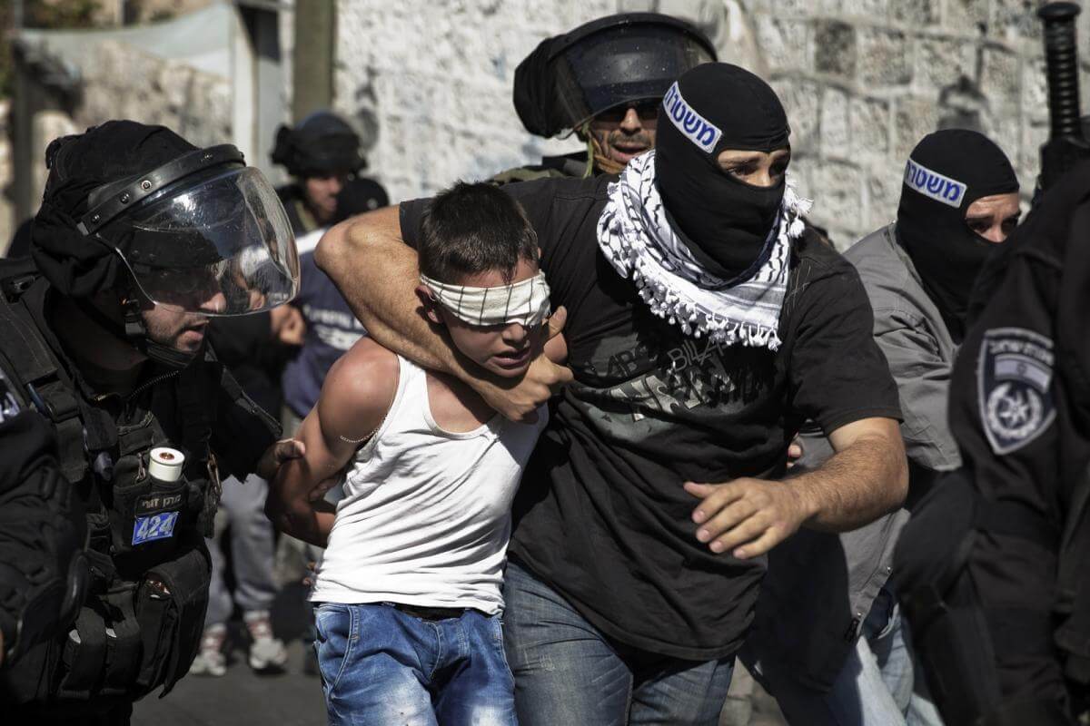 A Palestinian child being arrested in Jerusalem, f by masked Israeli police forces