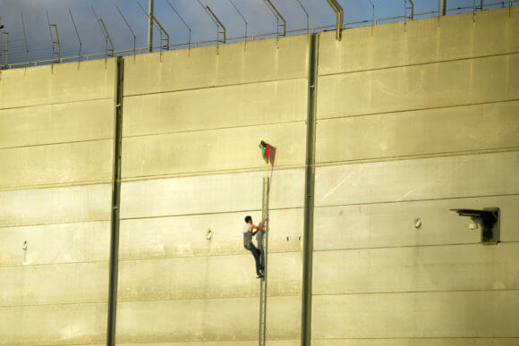 A Palestinian protester scaling the Gaza wall at the Karni crossing, July 20, 2018.