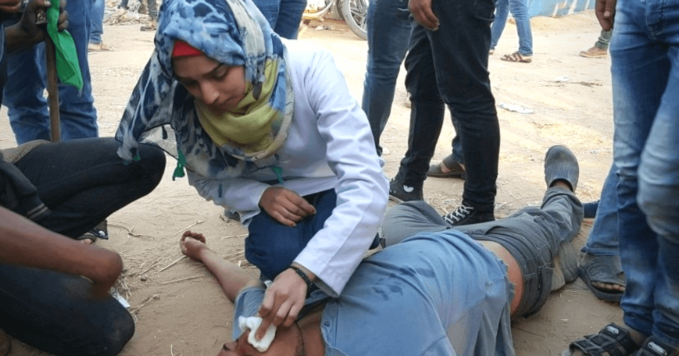 Razan al-Najjar, the 21 year old Gaza medic killed by an Israeli sniper on June 1, treating an injured man, undated photo from Palestine Live on Twitter.