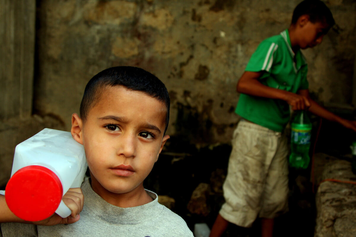 Palestinian boys fill bottles of water in the West Bank village of Qarawah Bani Zeid