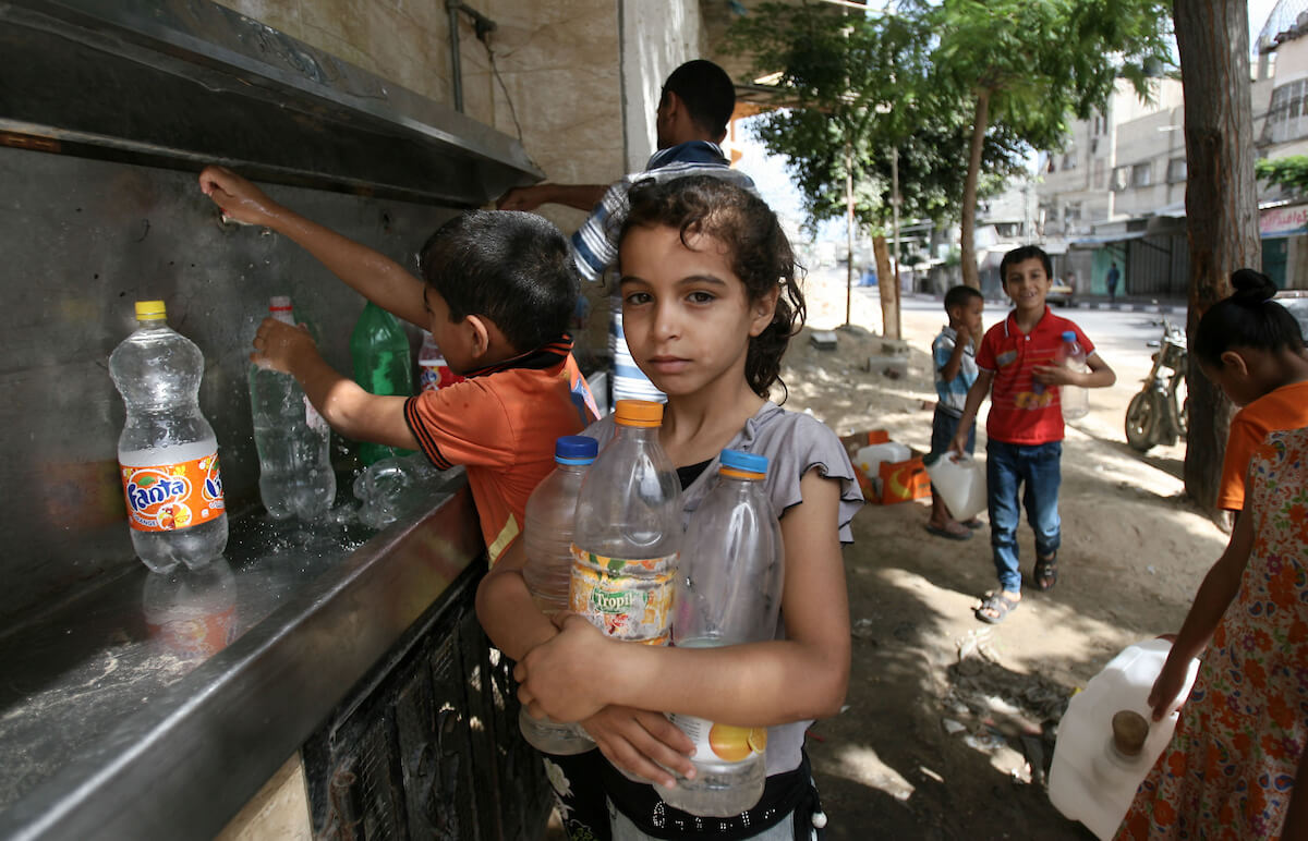 Palestinian children fill bottles with water from a public tap in Rafah in the southern Gaza Strip, July 1, 2014. Israel had bombed the main water line for al-Shati refugee camp and a sewage plant west of Gaza City. (Photo: Eyad Al Baba/APA Images)
