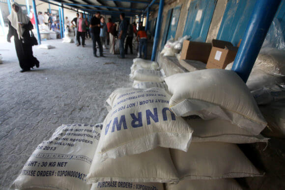 Palestinians receive food aid from UNRWA at a warehouse in al-Shati refugee camp in Gaza City, Sept. 10, 2013. (Photo: Ashraf Amra/APA Images)