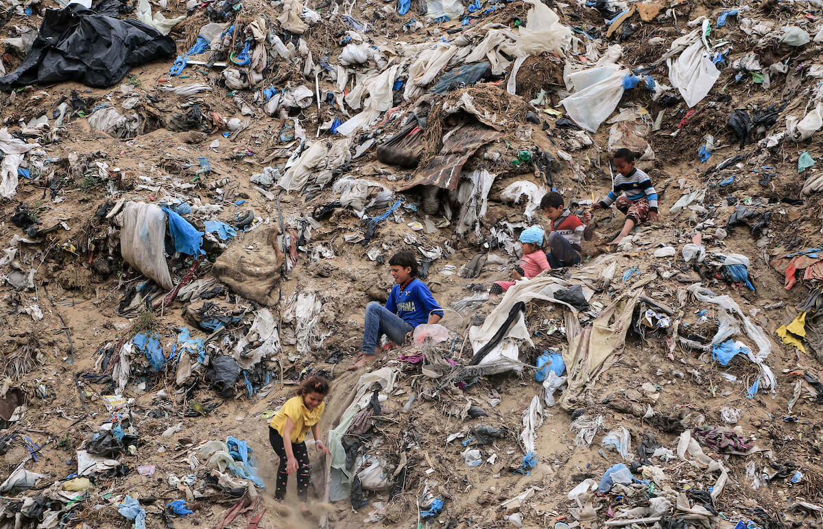 Palestinian children play on waste in an unofficial landfill at Nahr al-Bared refugee camp in Khan Younis in the southern Gaza Strip on April 16, 2019. (Photo: Mahmoud Khattab/APA Images)
