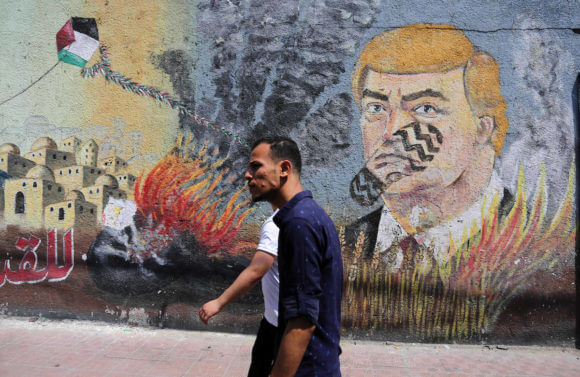 Palestinians walk past a mural depicting U.S. President Donald Trump, in Gaza City, June 24, 2019. (Photo: Ashraf Amra/APA Images)