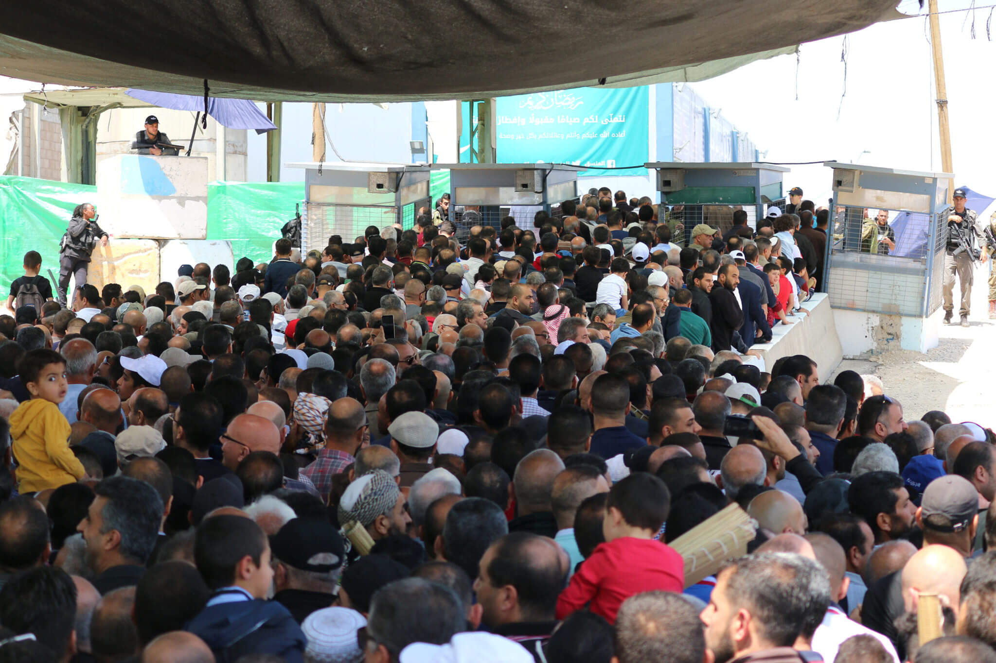 West Bank Palestinians stand in lines at the Qalandiya military checkpoint, May, 2019.(Photo: Ahmad Al-Bazz / Activestills)