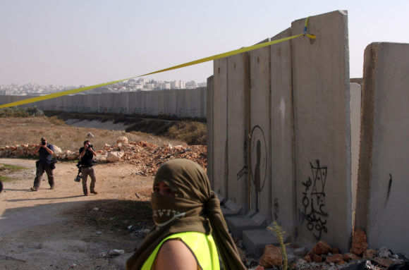 Palestinians mark the fall of the Berlin wall by removing a concrete block from Israel's controversial separation barrier during a protest in the Qalandia refugee camp near the West Bank city of Ramallah, on November 9, 2009. (Photo: by Issam Rimawi/APA Images)