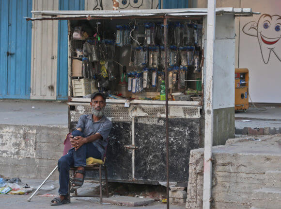 A Palestinian man sits next to his cart where he hangs household items for sell in al-Nuseriat refugee camp in the Gaza Strip (Photo: Mohammed Assad) Mondowiess)