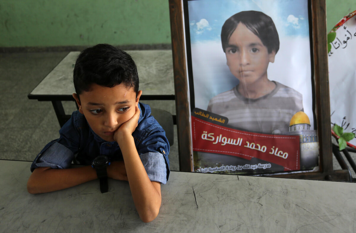 A picture of a Palestinian student, Moath Al Sawarka, who was killed in an Israeli airstrike on the Gaza Strip, is seen on his study seat next to his classmates at a school, in Deir al-Balah, the Gaza Strip on November 16, 2019. Israel said that it targeted Al Sawarka family and killed 8 people by mistake. (Photo: Ashraf Amra/APA Images)