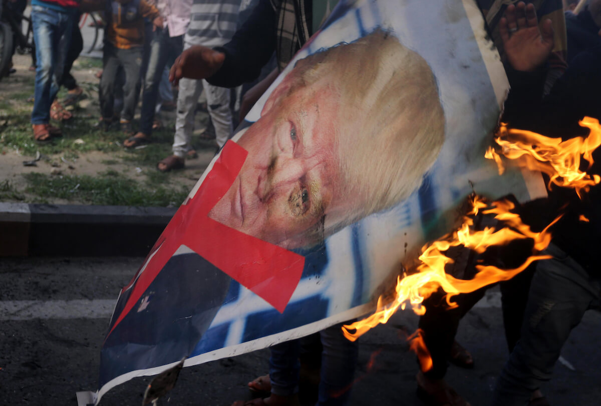 Palestinians burn posters depicting U.S. President Donald Trump during a protest against Trump's decision to recognize Jerusalem as the capital of Israel, in al-Bureij in the central of Gaza strip, December 15, 2017. (Photo: Ashraf Amra/APA Images)